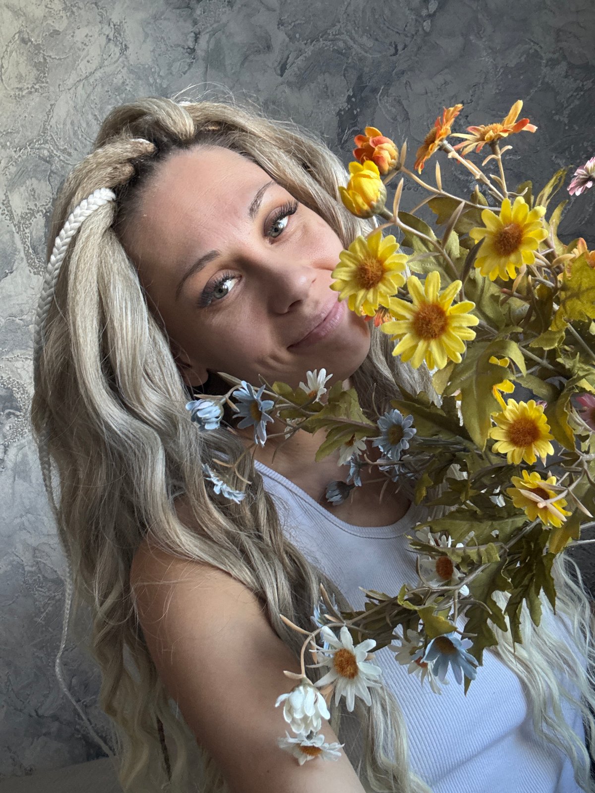 Woman poses with flower crown on gray surface in Russia