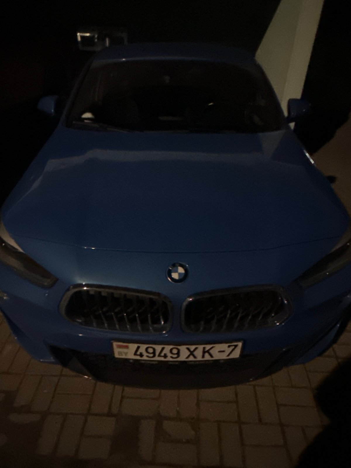 Cars parked on brick pavement during Minsk evening