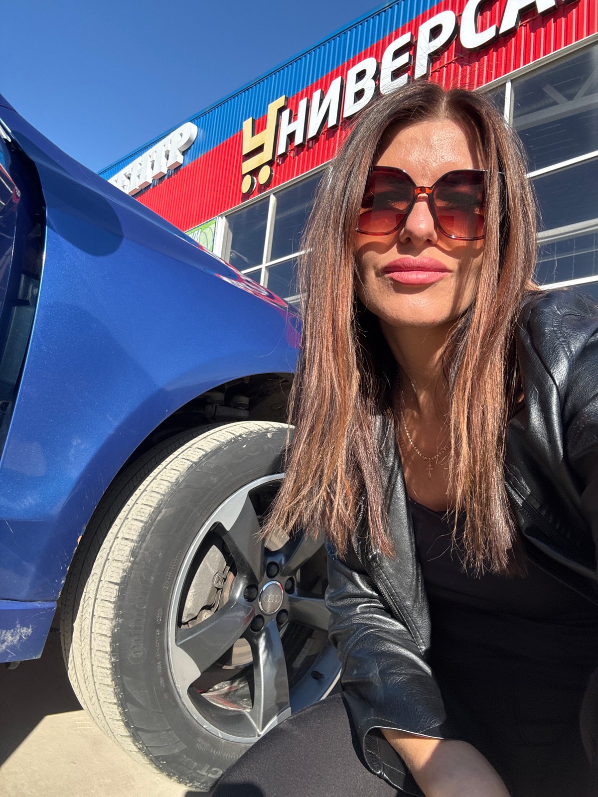 Woman documented around Chaikovsky with blue car during afternoon