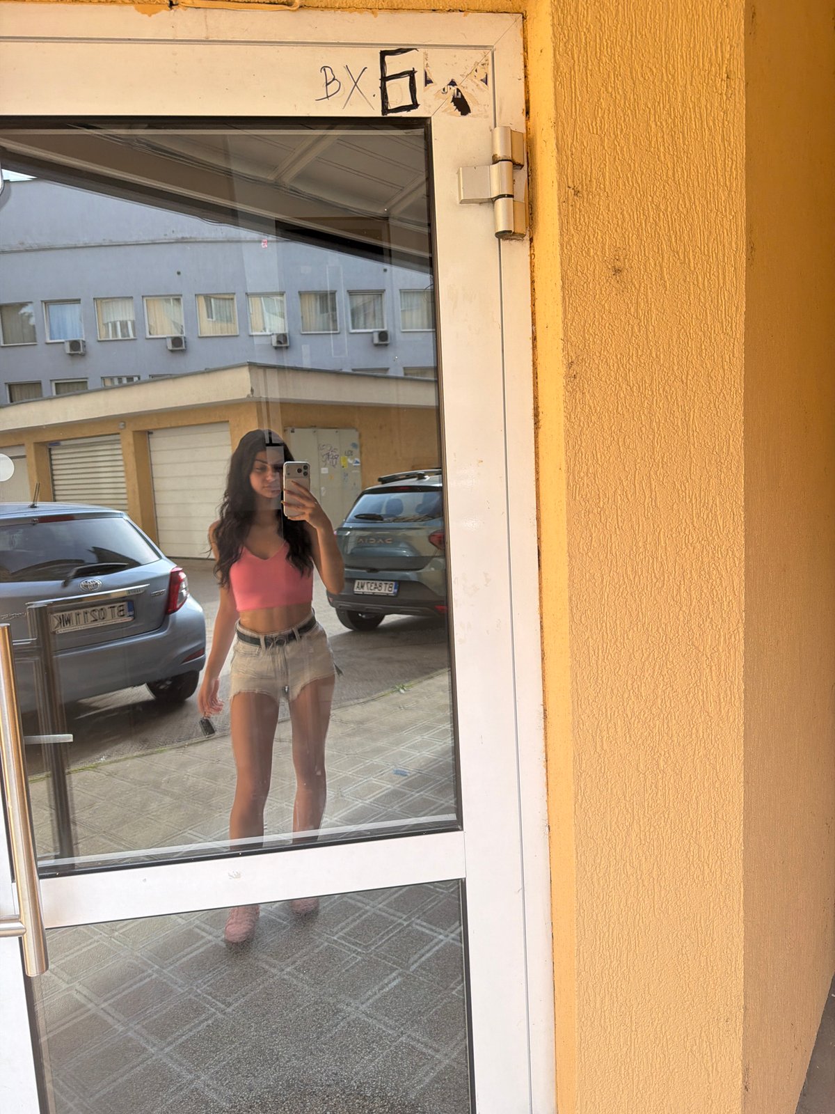 Woman takes mirror selfie at glass door in Veliko Tarnovo