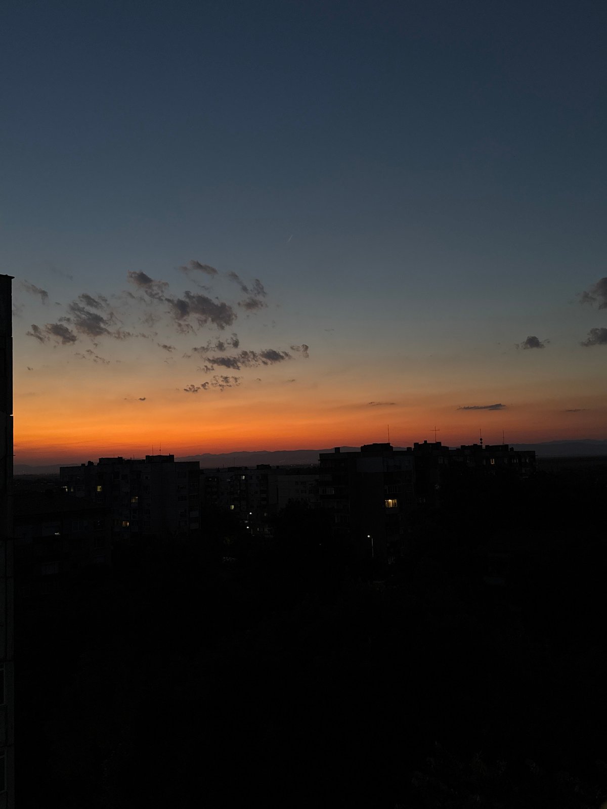 City skyline at golden hour, sky fading blue to orange