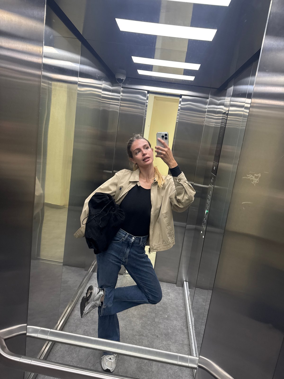 Woman takes elevator selfie with smartphone in mirrored interior