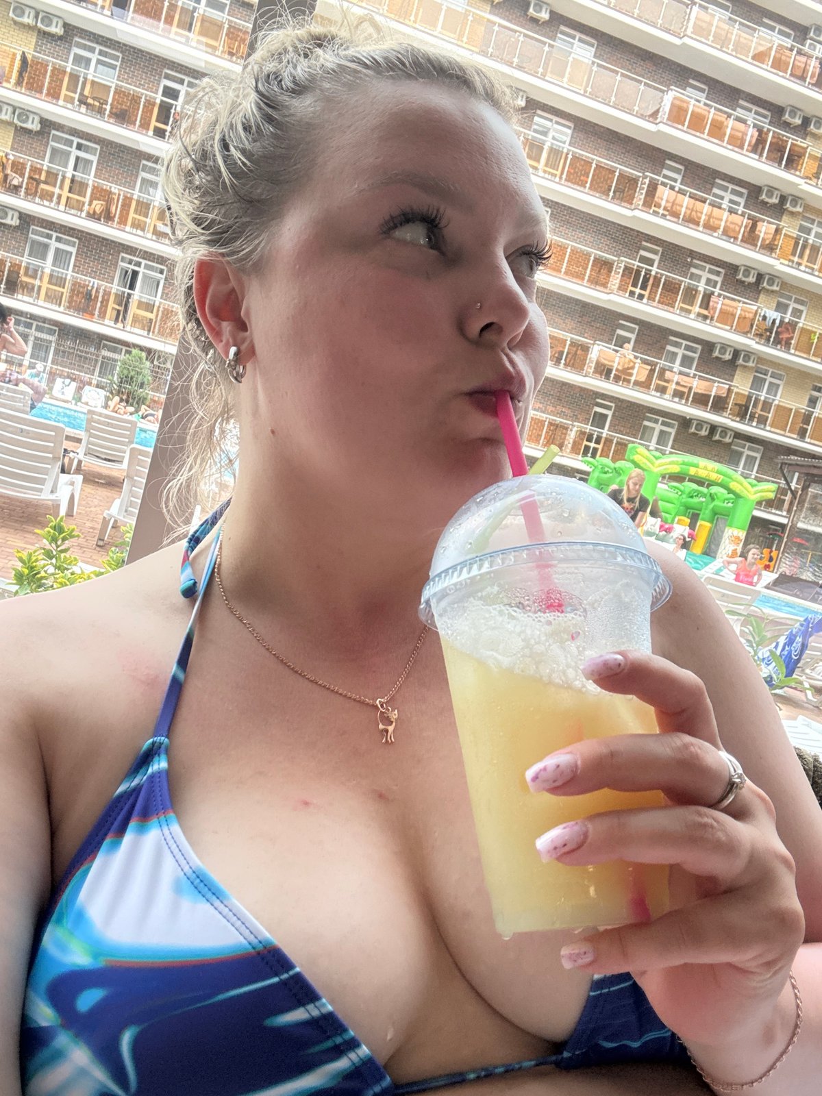Woman enjoys poolside drink at indoor facility