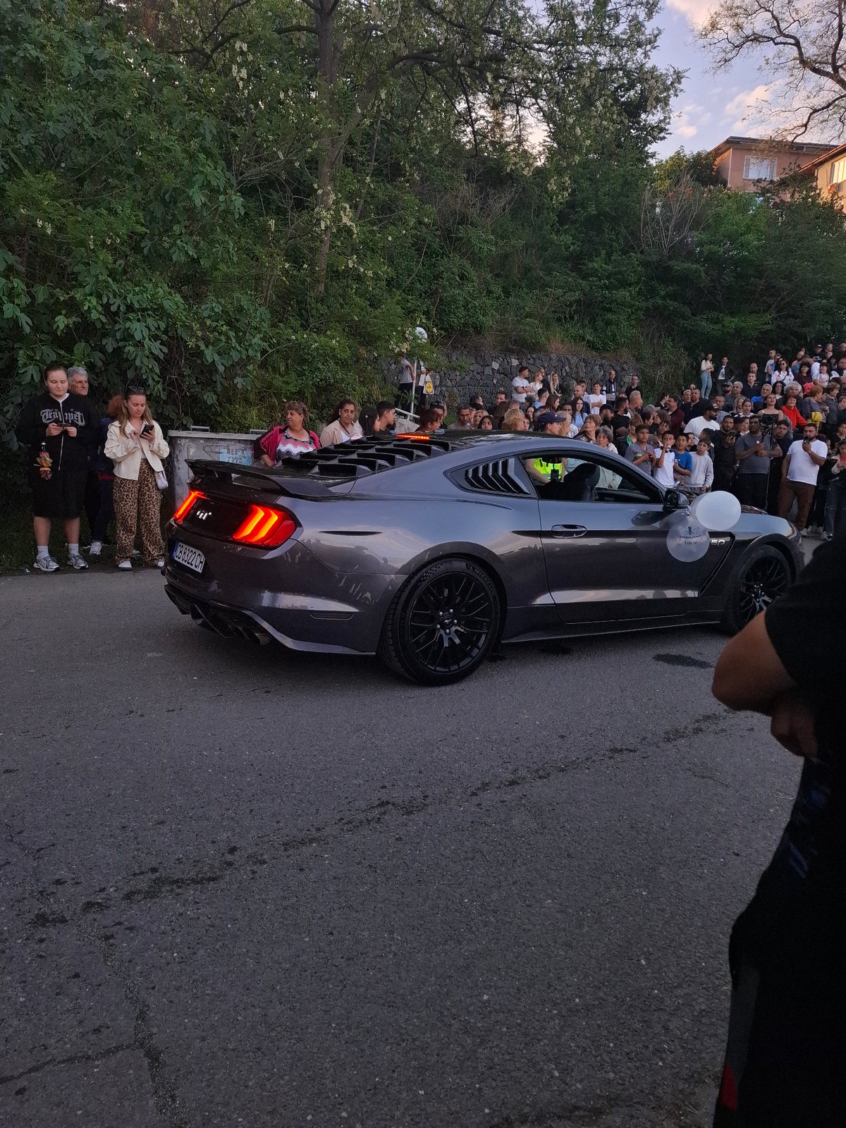 Crowd gathers around cars with flowers in Tsarevo Bulgaria