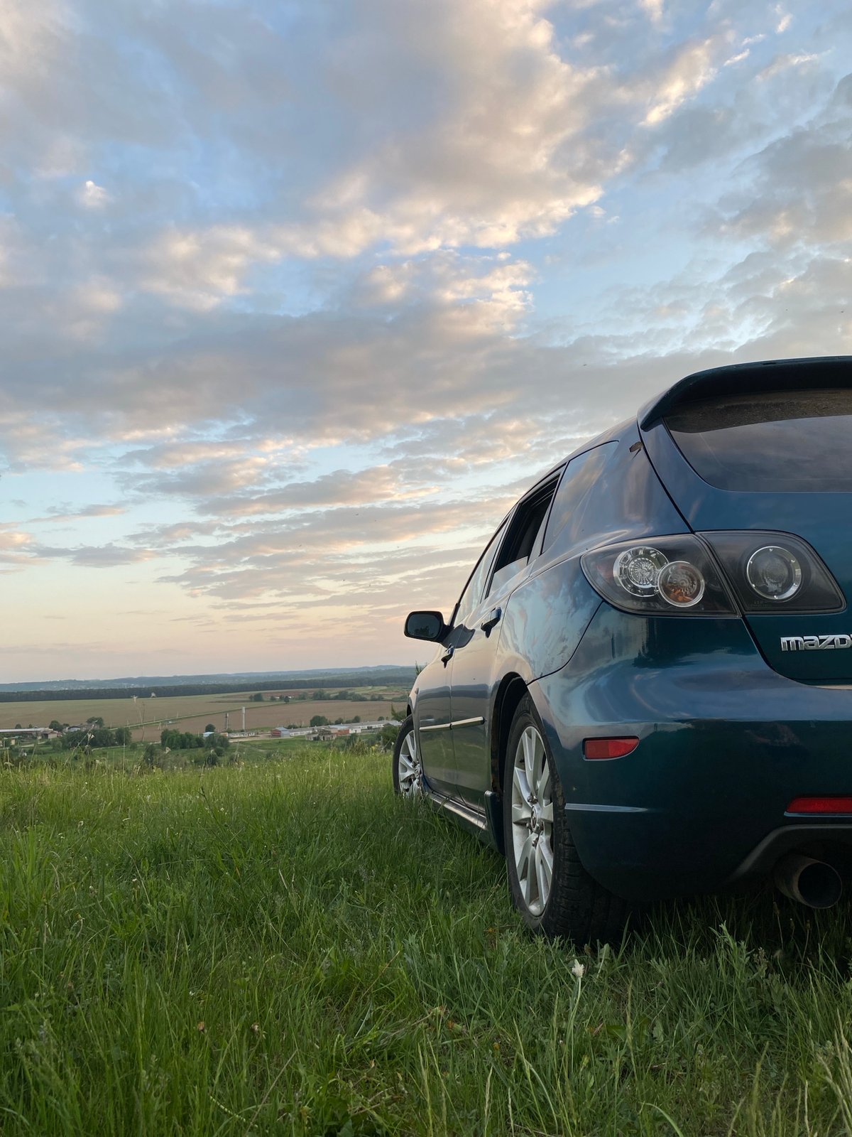 Sunset gathering with blue car in rural field