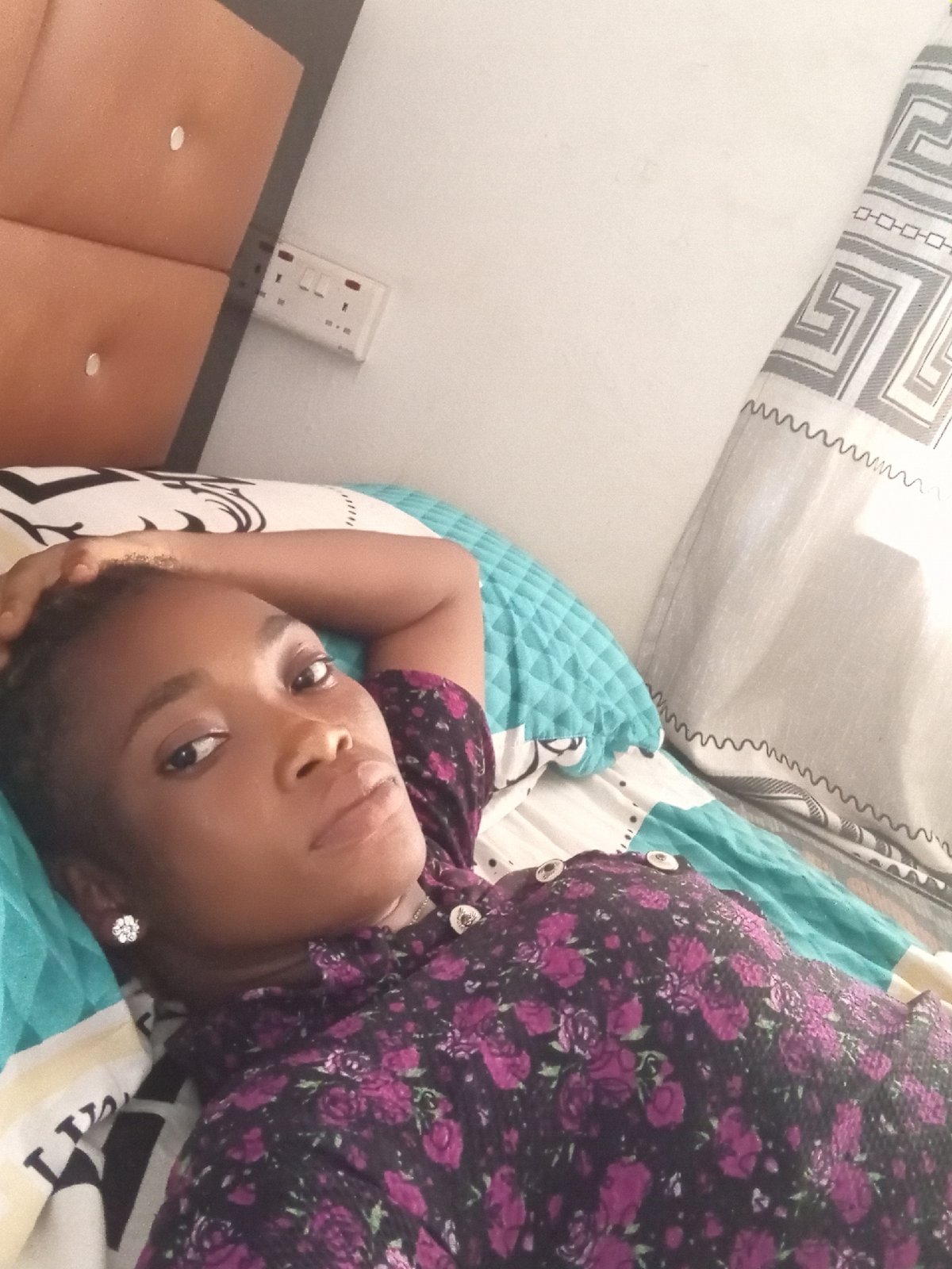 Woman rests on bed in Shagamu, Nigeria afternoon