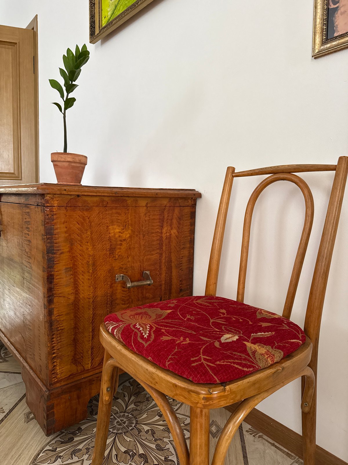 Antique chest, embroidered curtains, and flowers in a still interior
