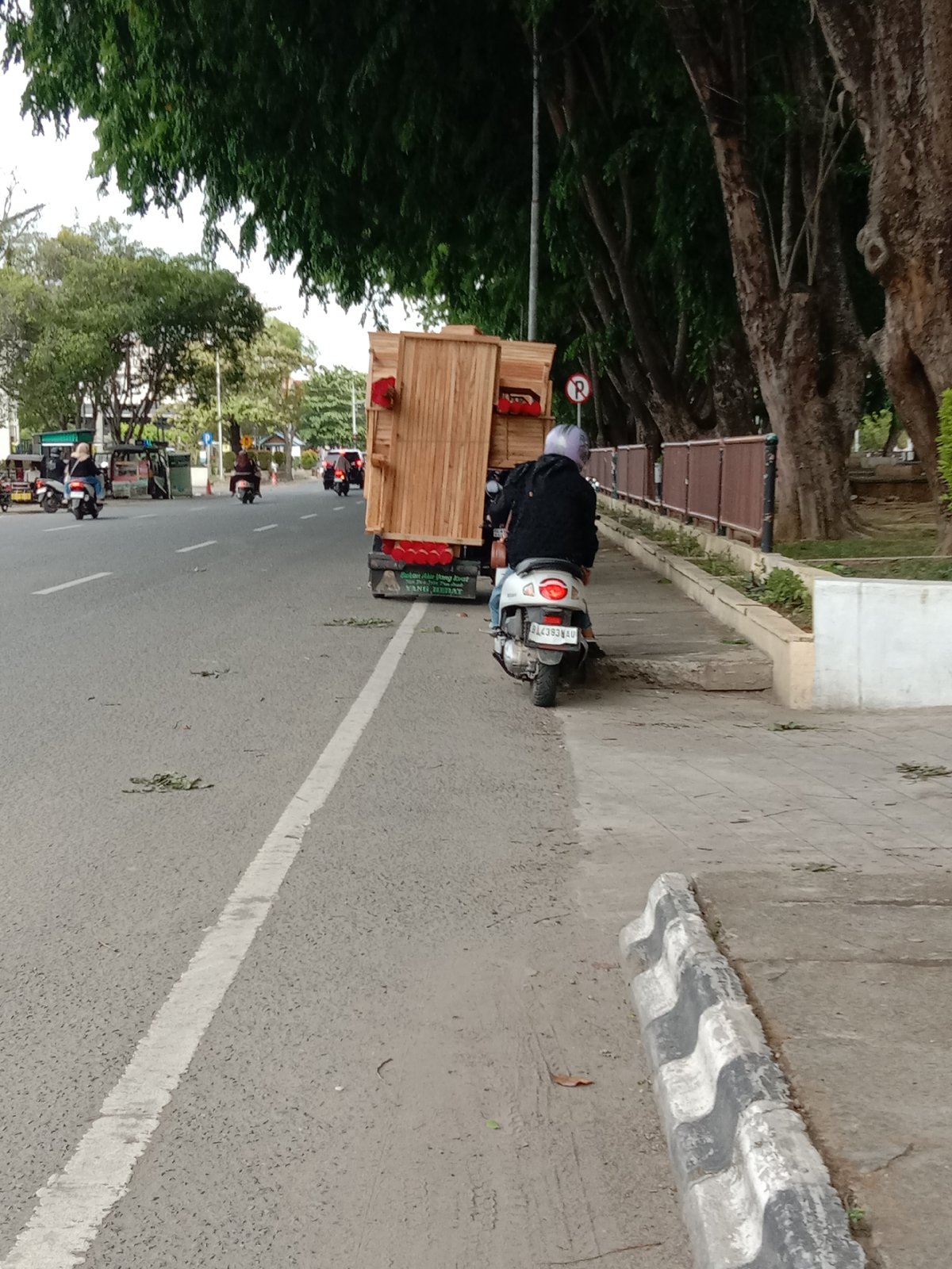 Scooter rider transports large wooden structure on city street