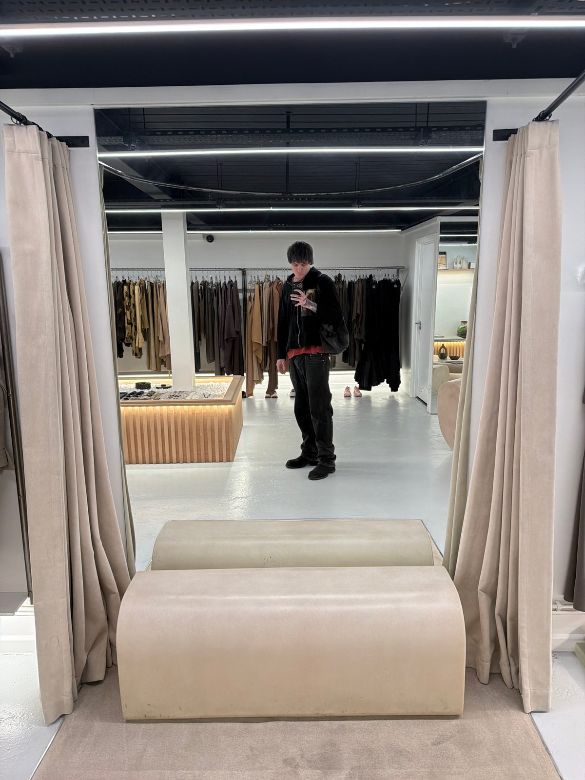 Person tries on dark clothing in London store fitting room