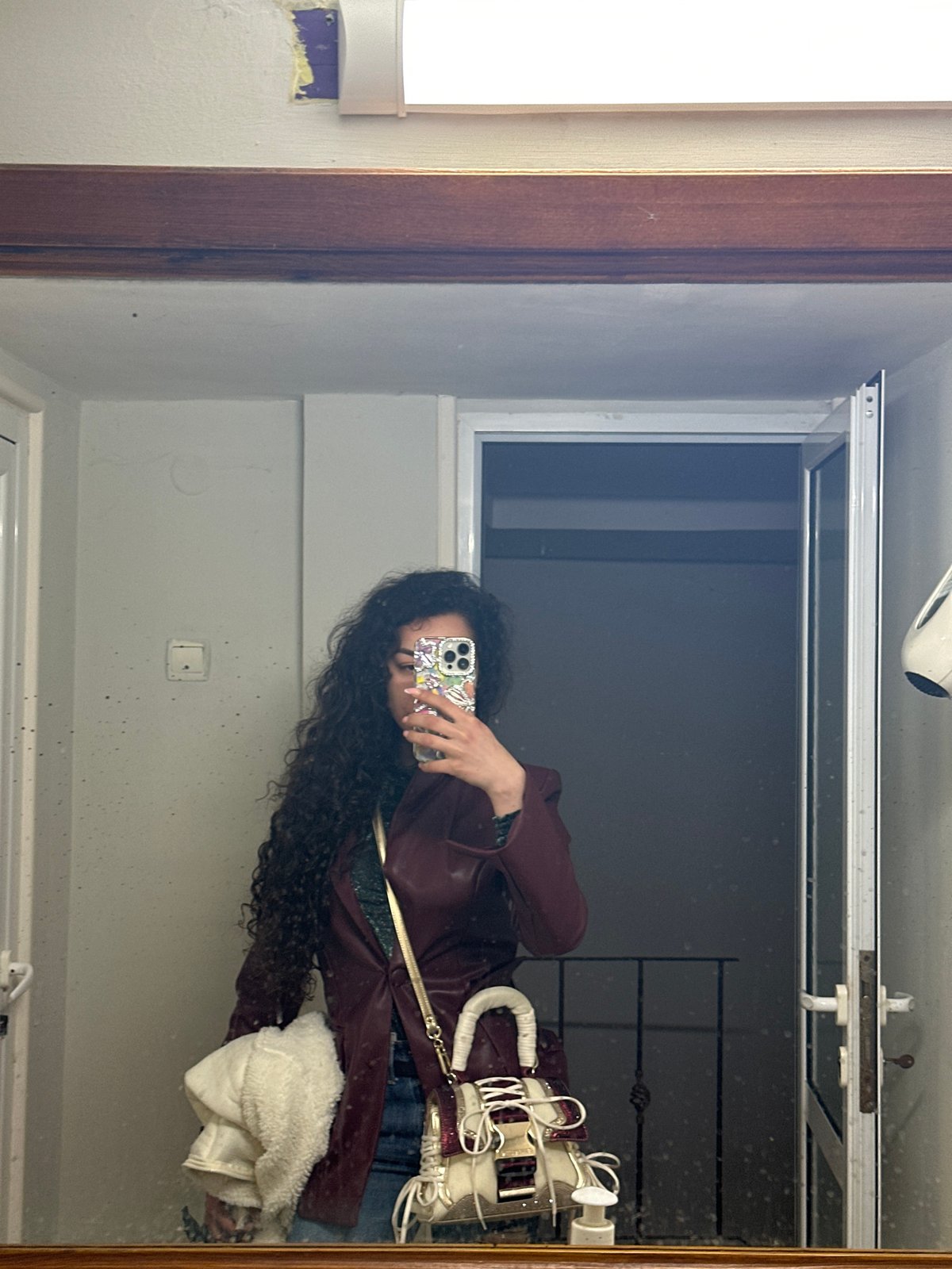 Mirror selfie captured showing person in maroon jacket