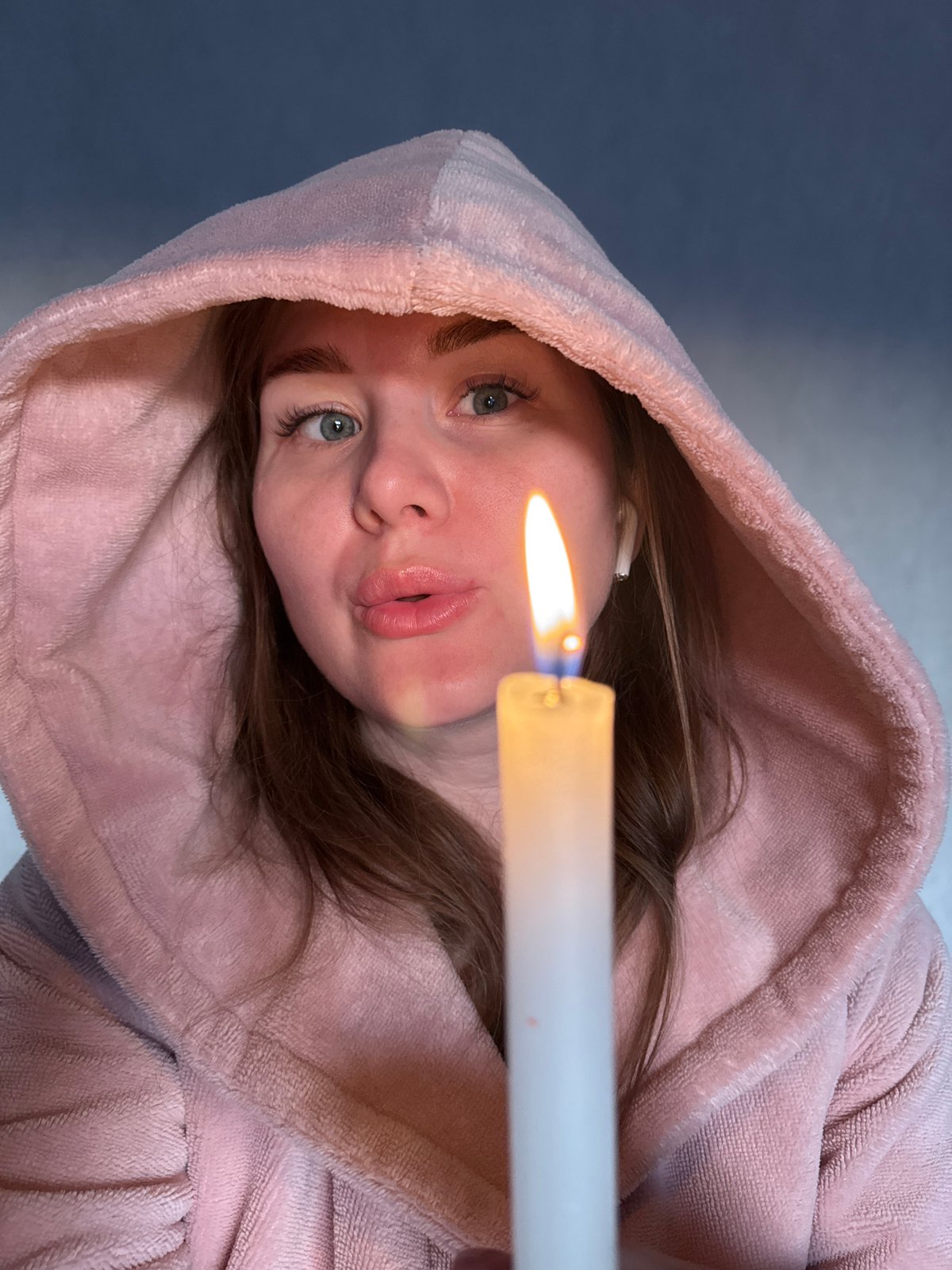 Woman holds candle in pink robe in Russian village