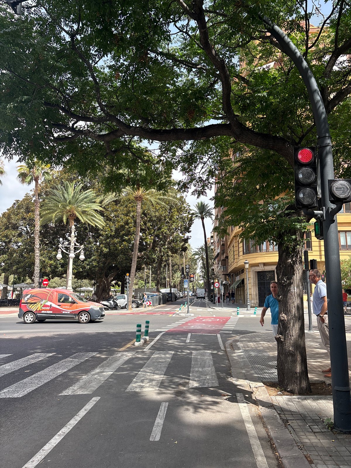 Valencia intersection with bus, van, and pedestrians near green space