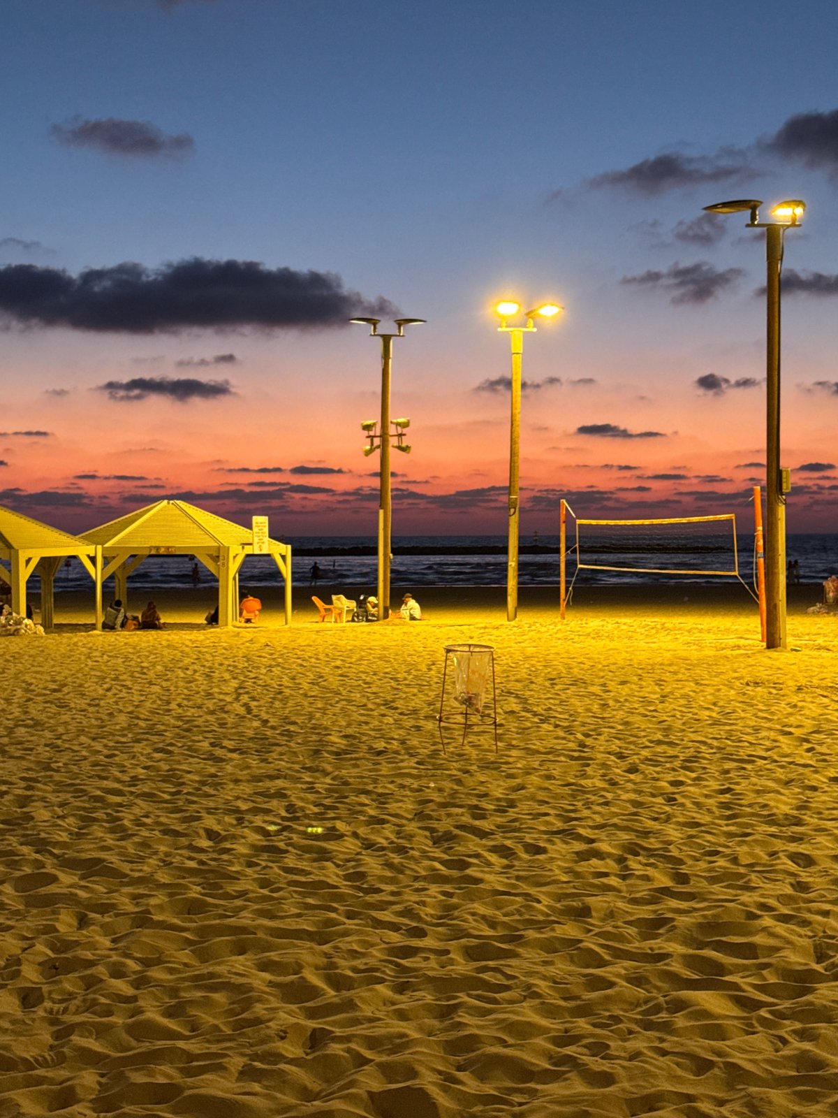 Tel Aviv beach at dusk, sky fading through pink and orange