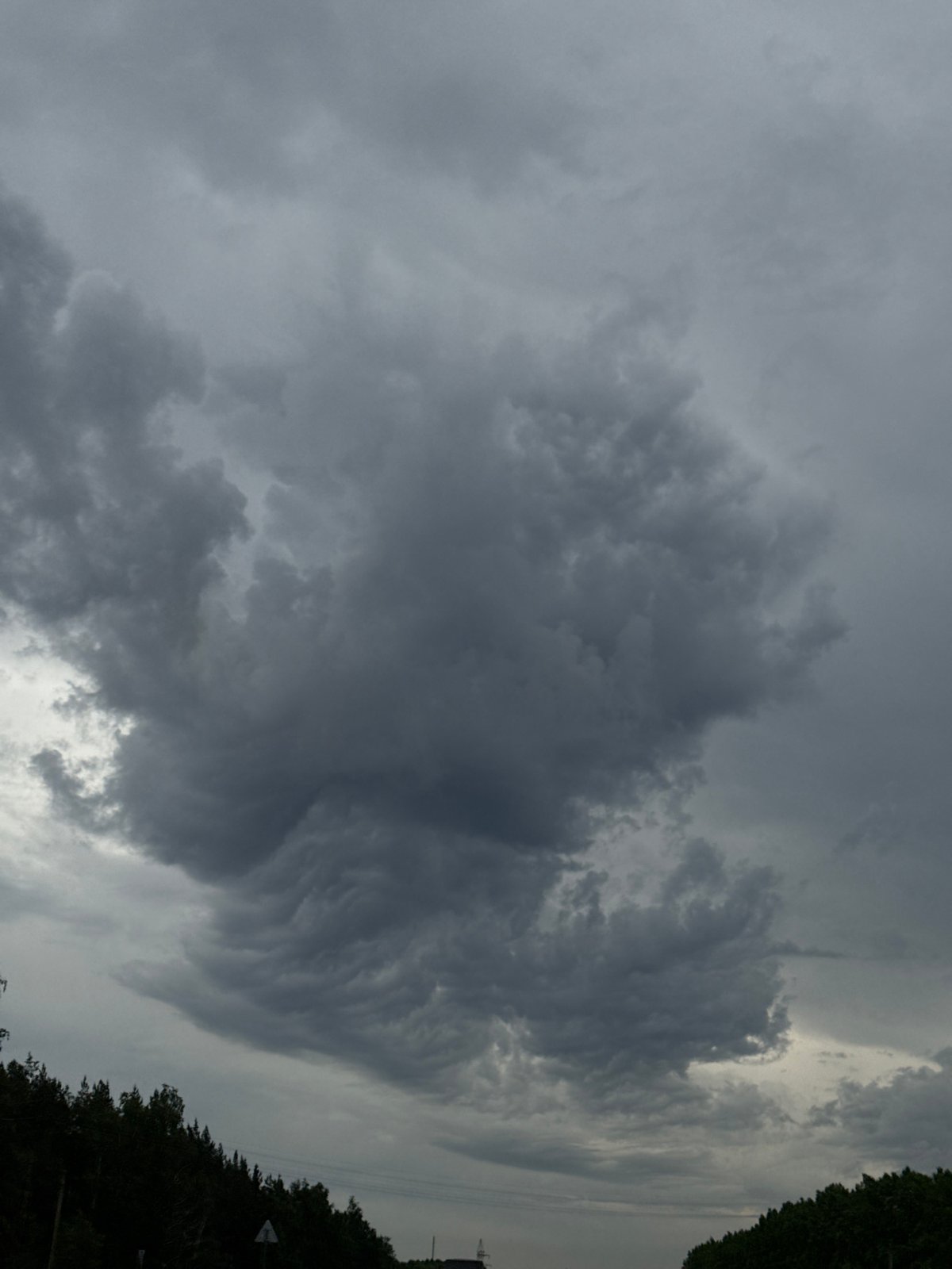 Heavy clouds gather over rural road in Бизяки, Russia