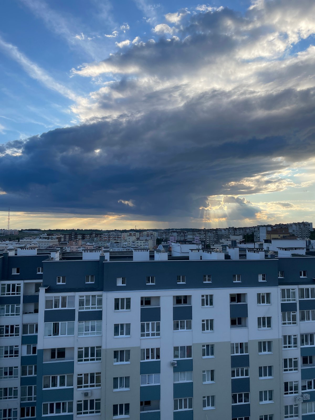 Sunbeams break through storm clouds over a residential skyline