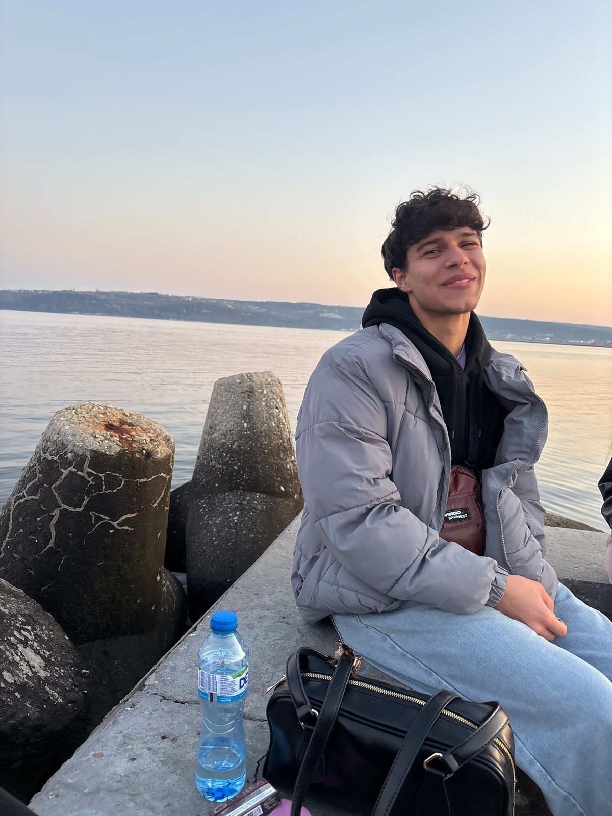 Two people sit on waterfront concrete structure