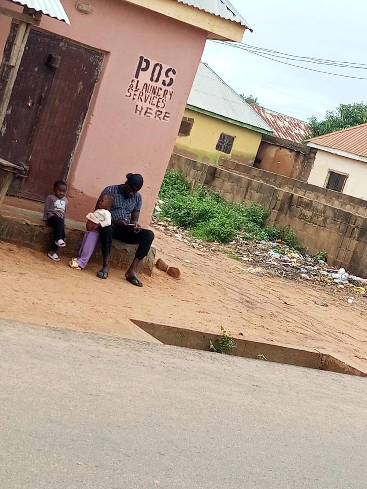 Morning street life outside a pink building in Tempure, Nigeria