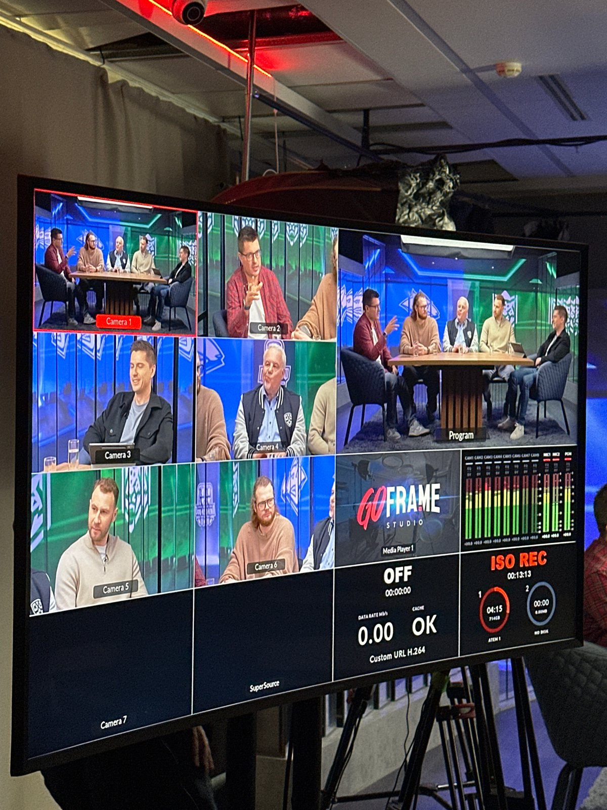 Five men filmed at table during broadcast production session