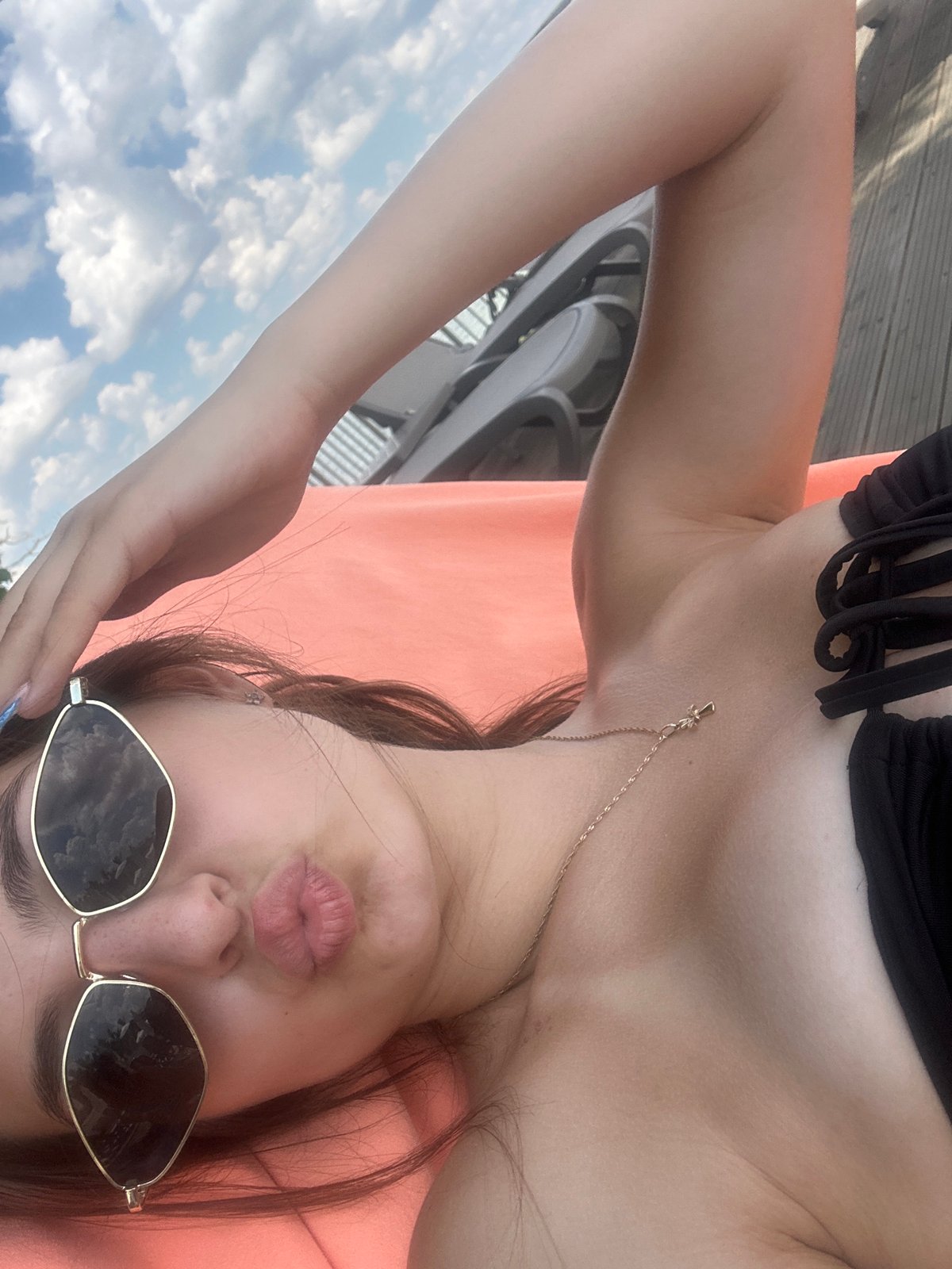 Lounging in the sun on a resort deck, black bikini and gold accessories.