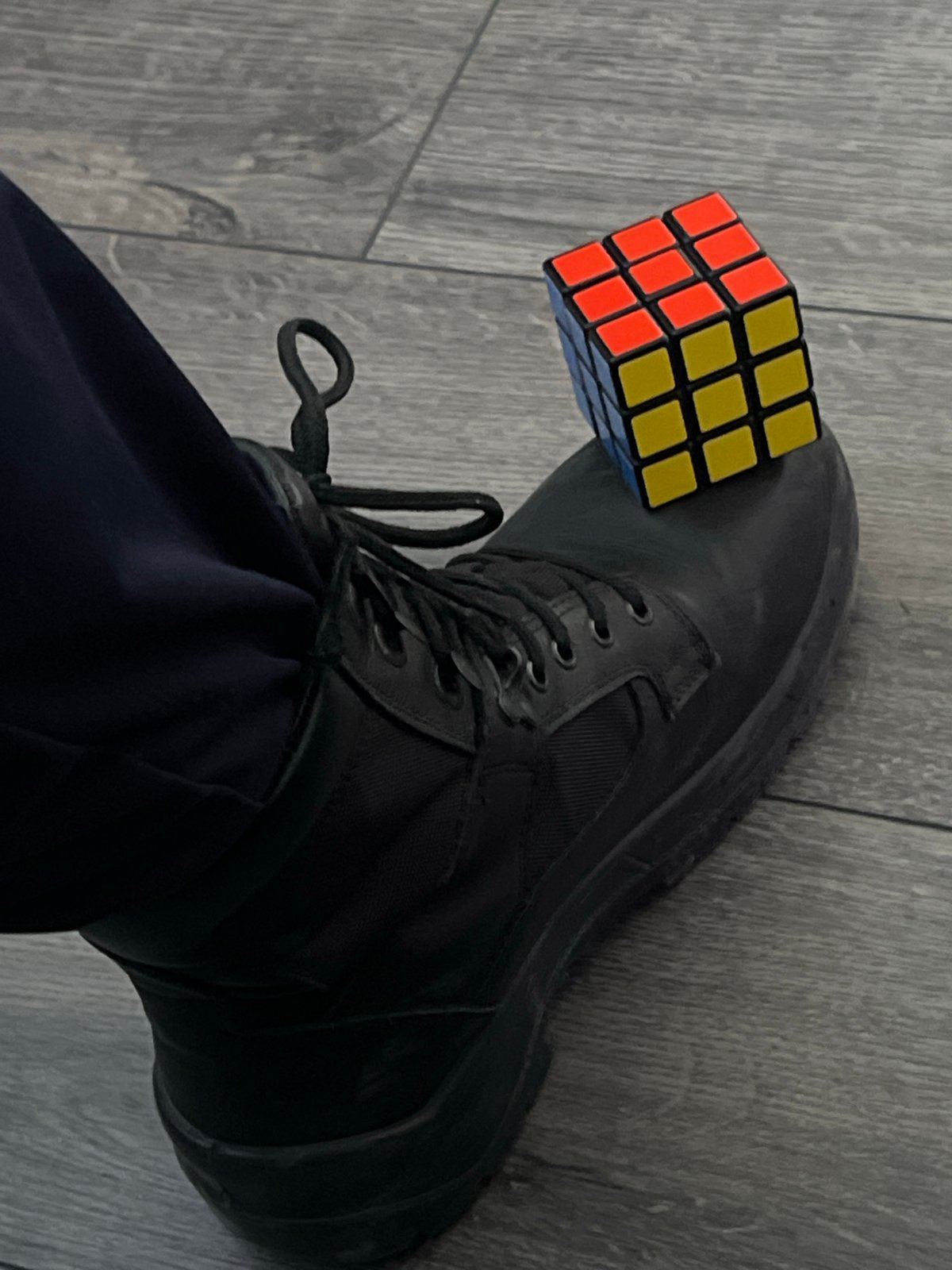 Person in uniform clothing observed with Rubik's Cube boot display
