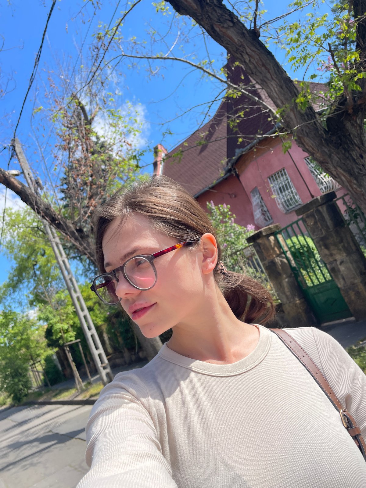 Woman documents sunny morning walk through residential Budapest neighborhood