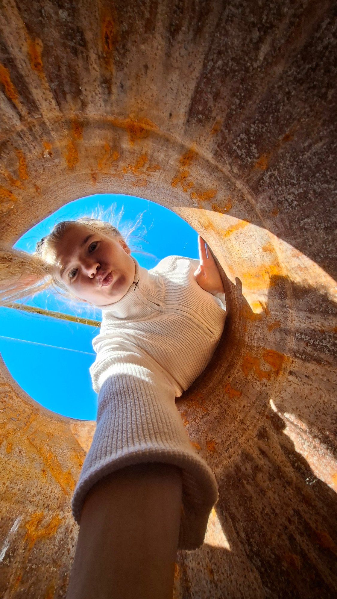 Woman explores flowers and rusty pipe in Russian village