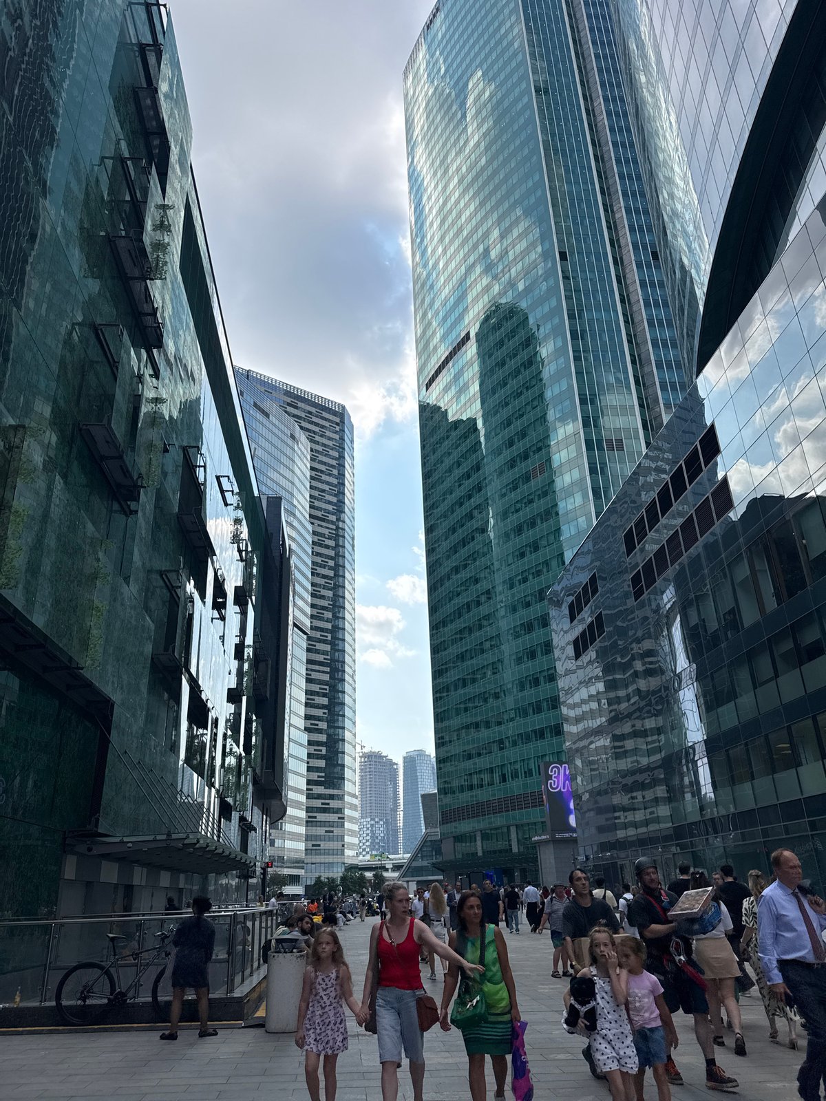 Busy pedestrian walkway cuts through a gleaming downtown high-rise district