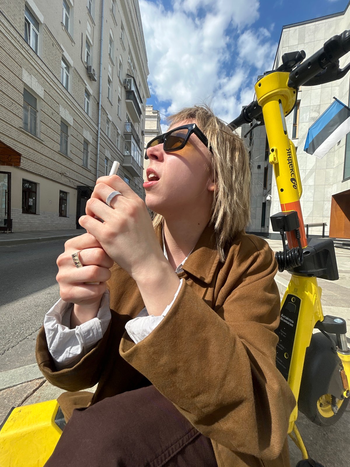 Woman on Yandex scooter smoking in urban setting