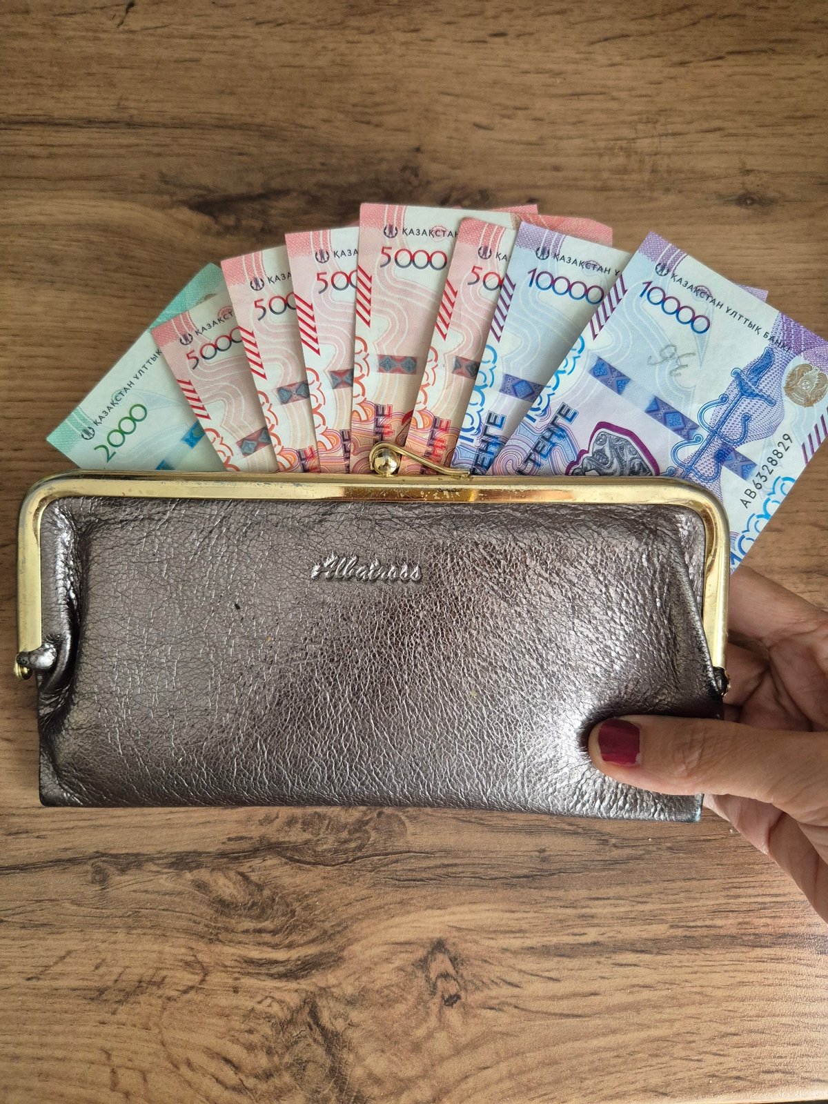 Person counts stack of Kazakhstani tenge banknotes in Kokshetau