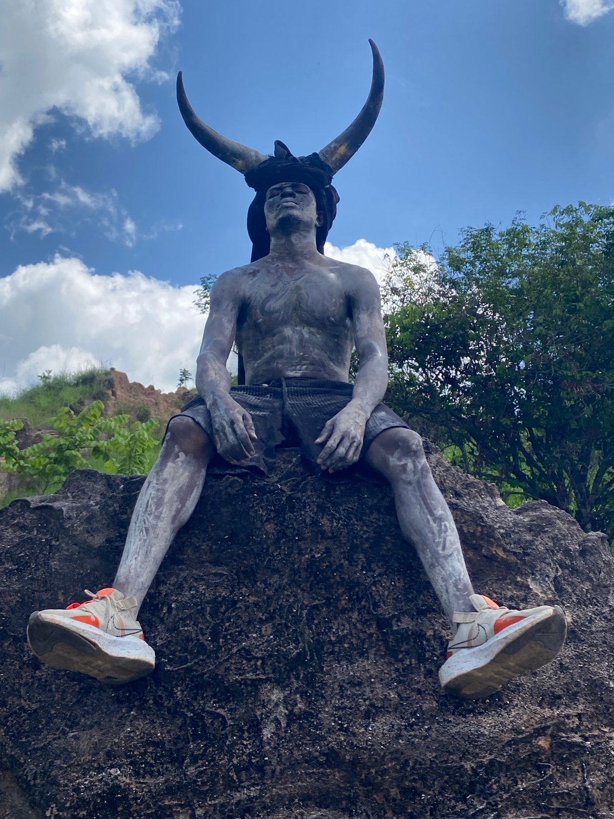 Person in grey paint, horns spotted on rocks in Nigeria