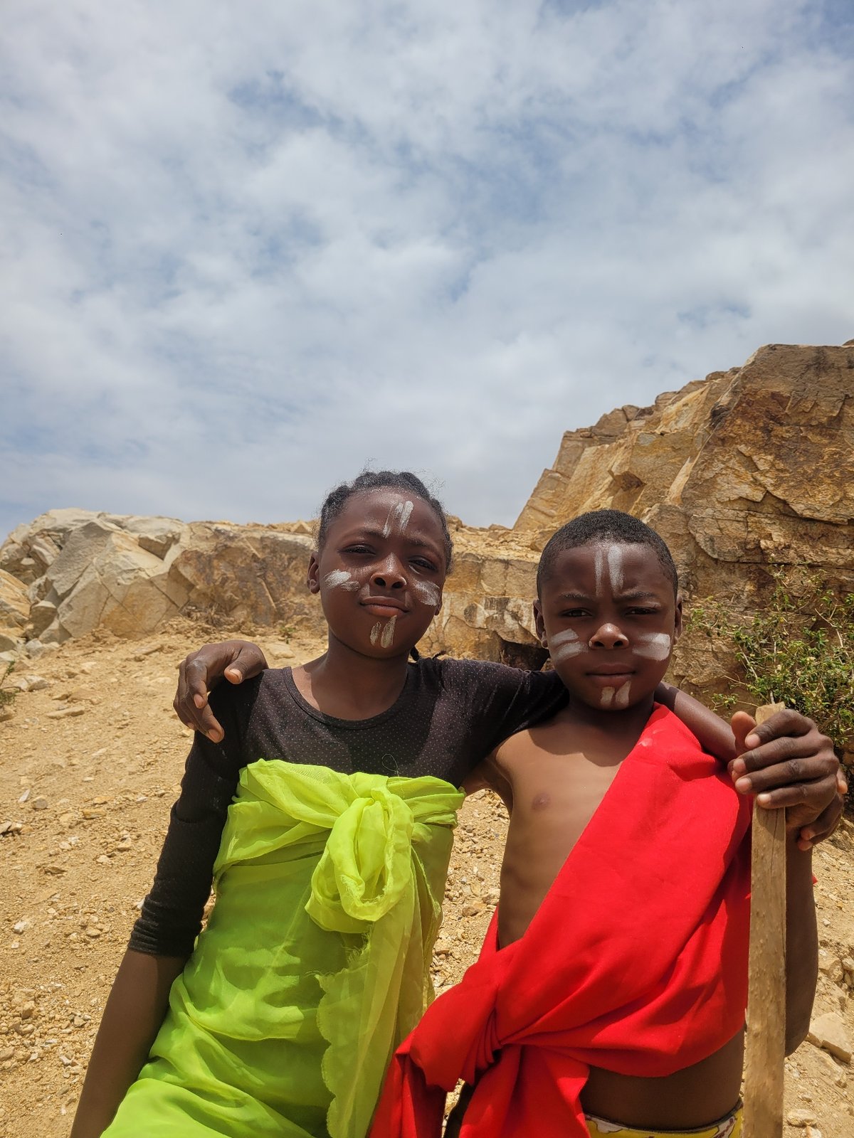 Children with face paint gather in rocky terrain, Barakin Akawo