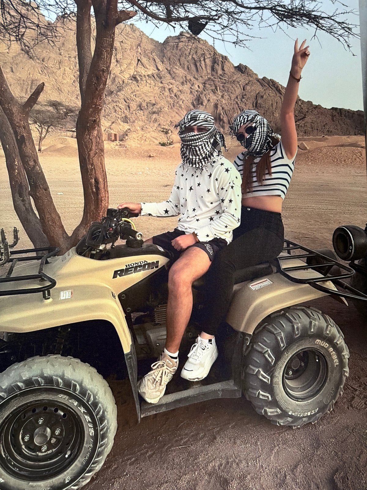 Two people on a Honda ATV in a rocky desert landscape