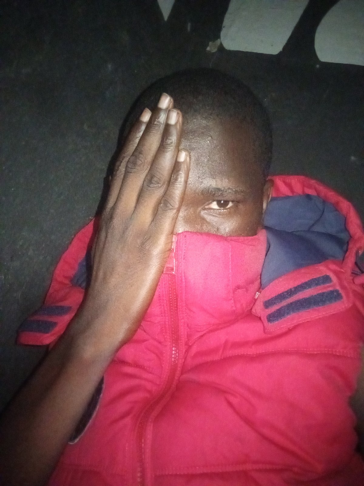 Person in red jacket observed covering face indoors