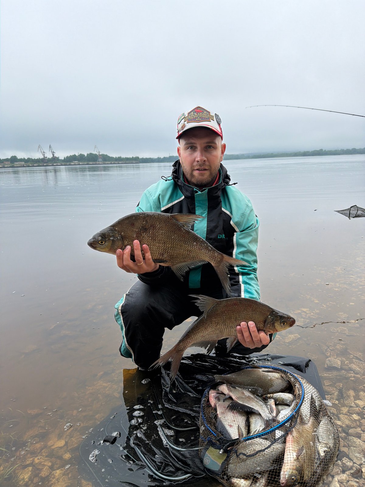 Fisherman displays catch in shallow waters near Chaikovsky, Russia