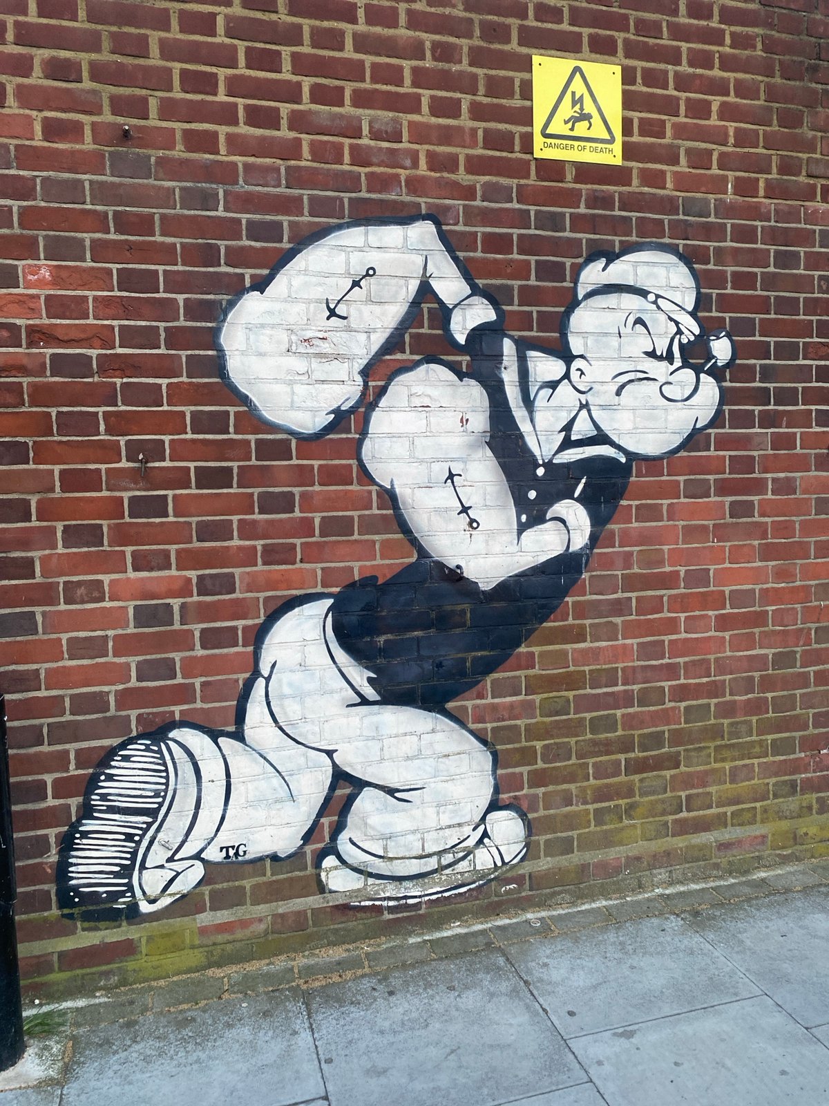 Popeye graffiti spotted on London brick wall near warning sign