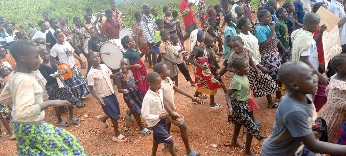 Children and adults march with banners in DRC communities