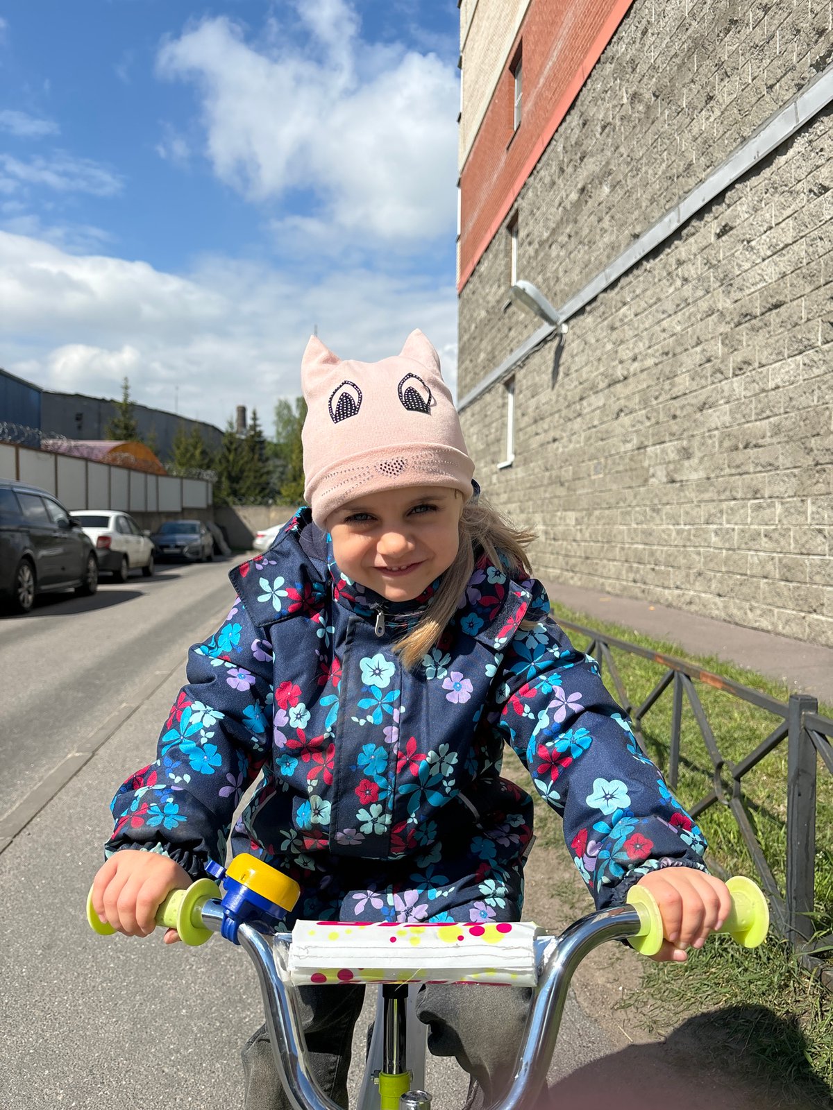 Girl with cat-eared hat bikes around Saint Petersburg with doll
