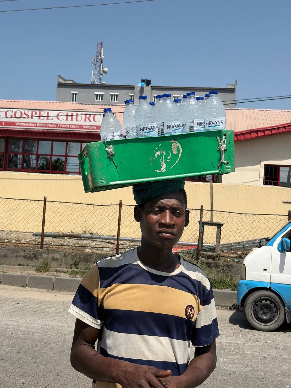 Street vendor carries water bottles in sunny Igboefon, Nigeria