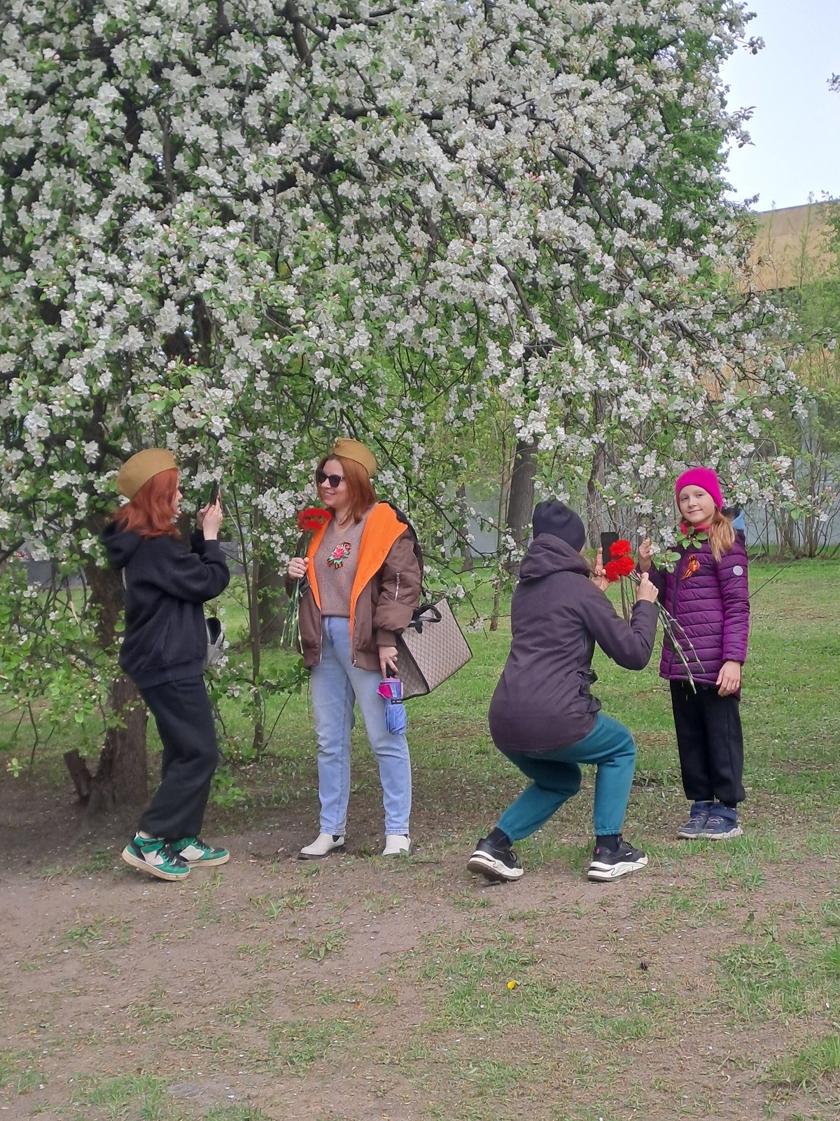 Four people gather near blooming tree in Elektrostal park