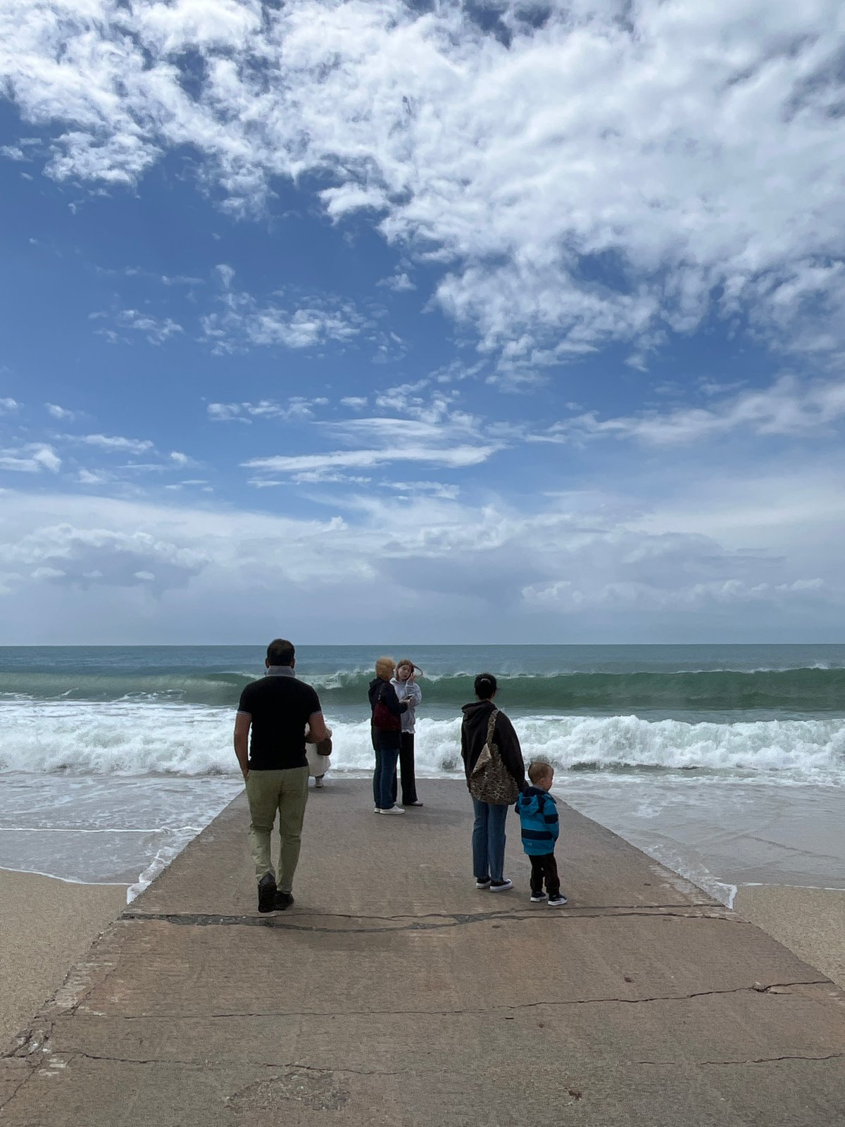 Four people gather on pier overlooking choppy Mediterranean seas