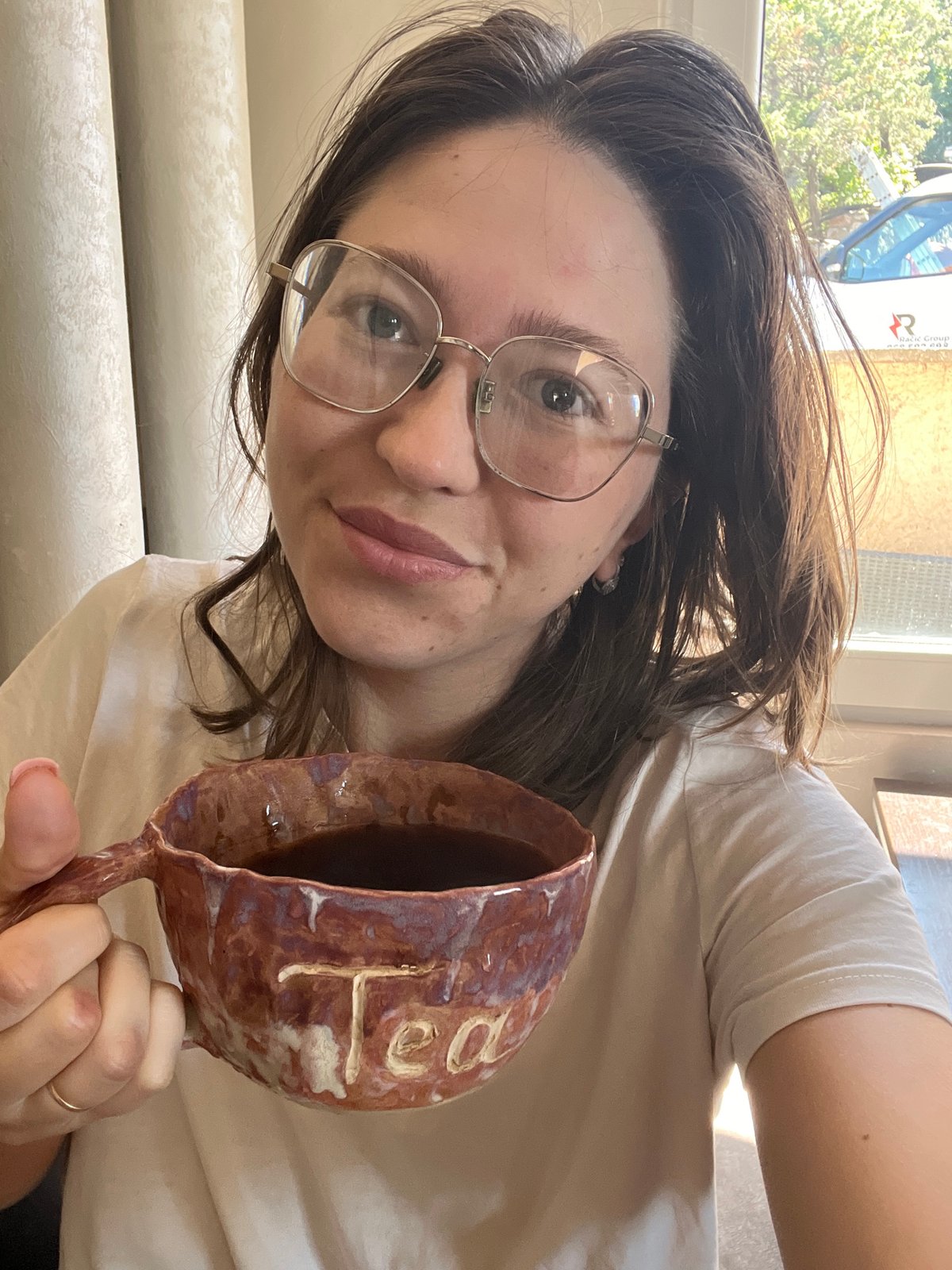 Woman displays ceramic mug indoors in Podgorica