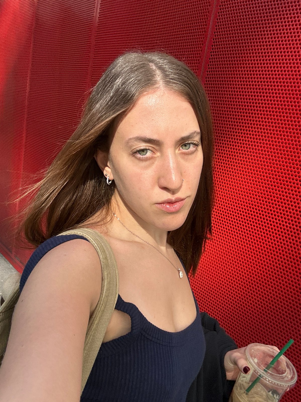 Woman takes selfie with drink against red wall in Mexico City