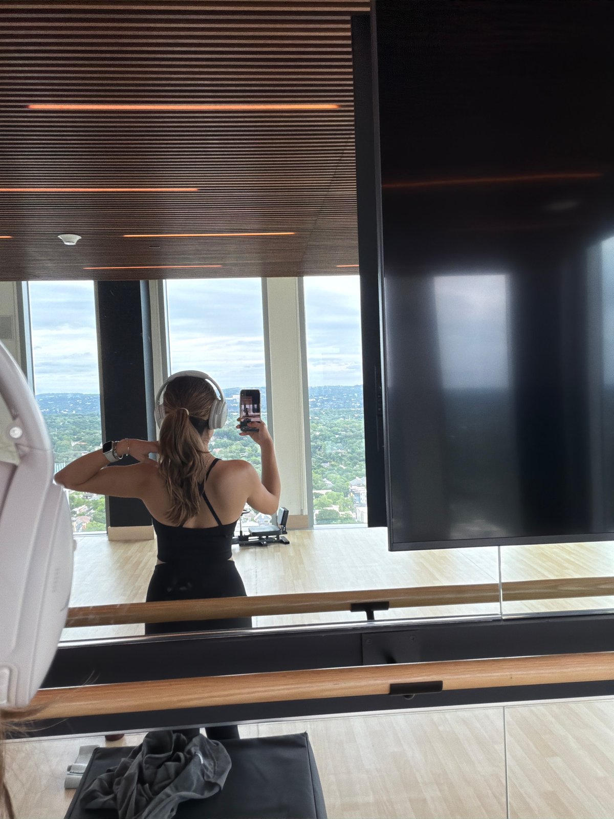 Woman takes selfie by window in Austin workout gear