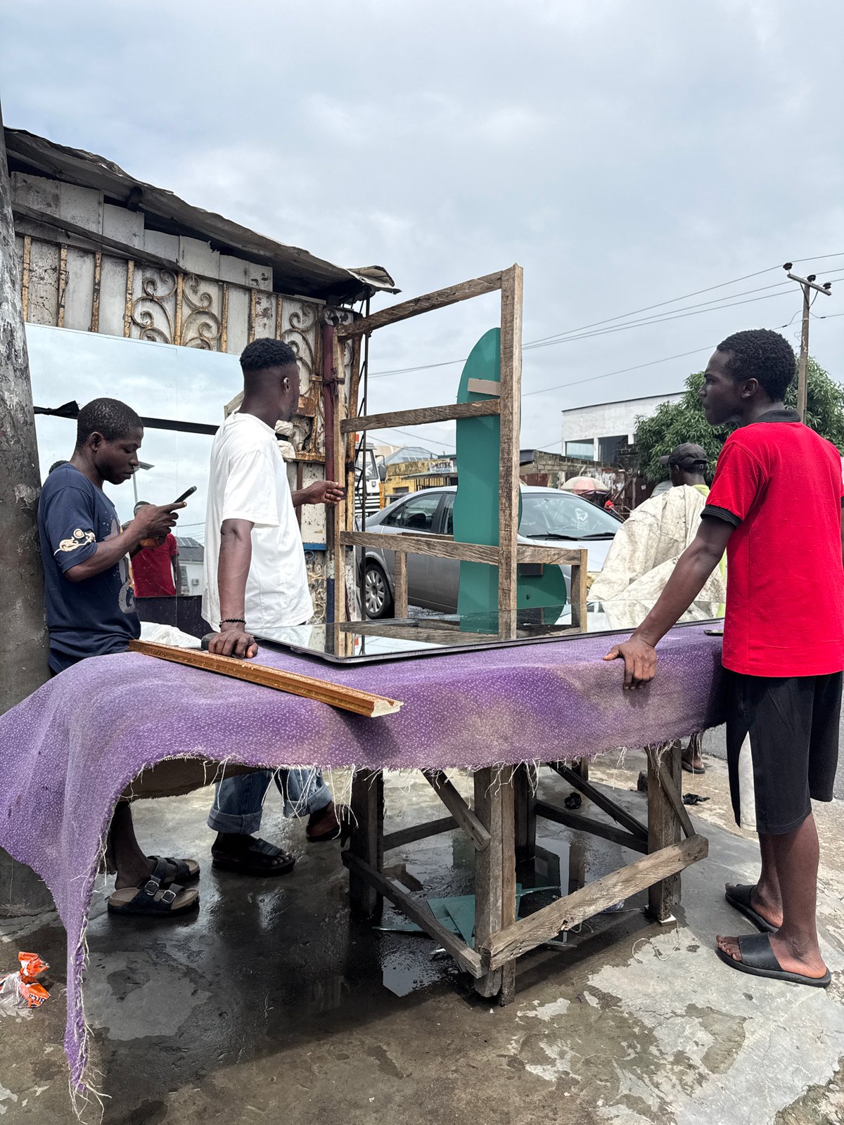 Wet morning street activity across a busy Ado, Nigeria neighborhood