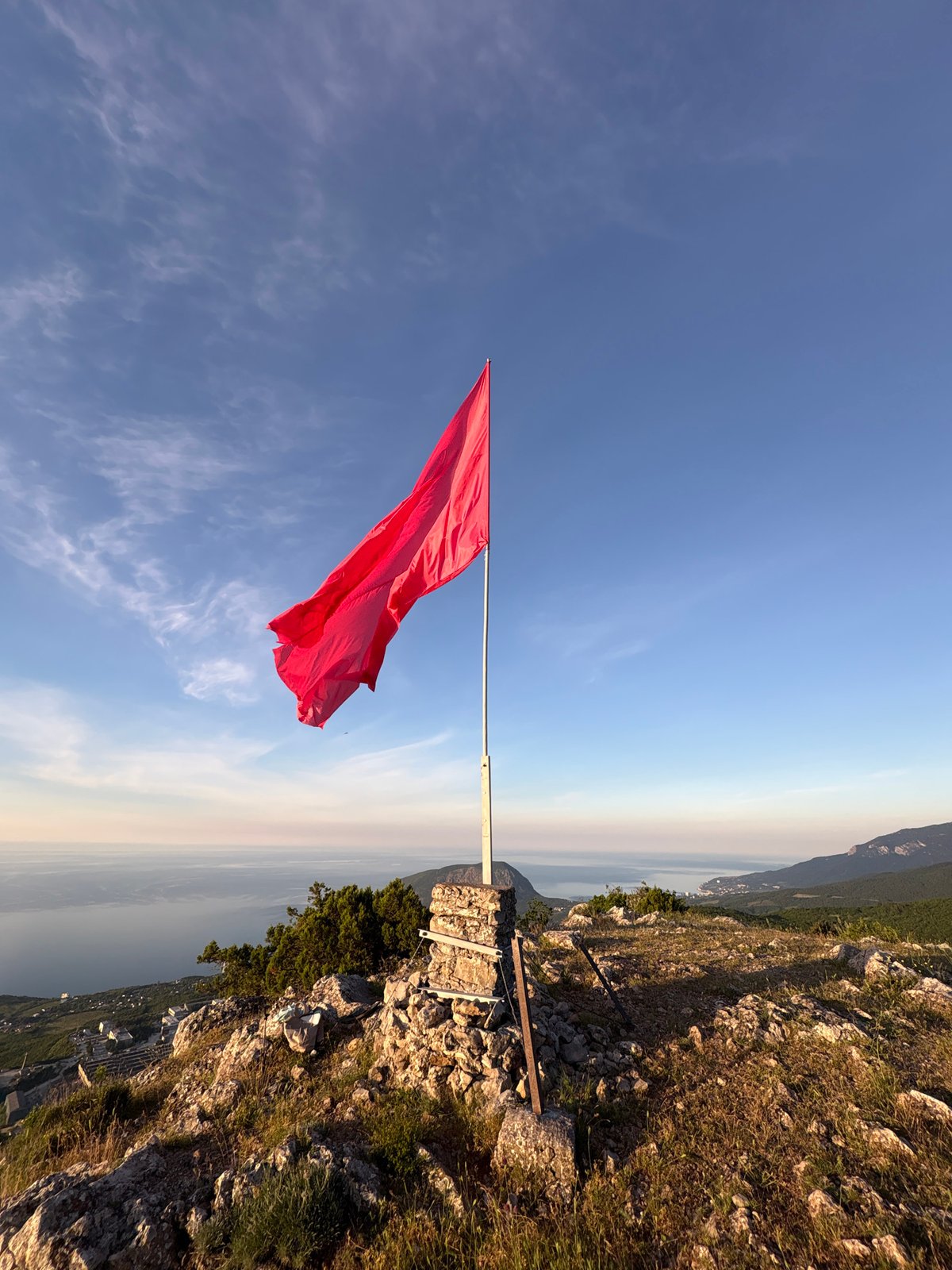 Woman documents mountaintop sunrise with red flag in Ukraine