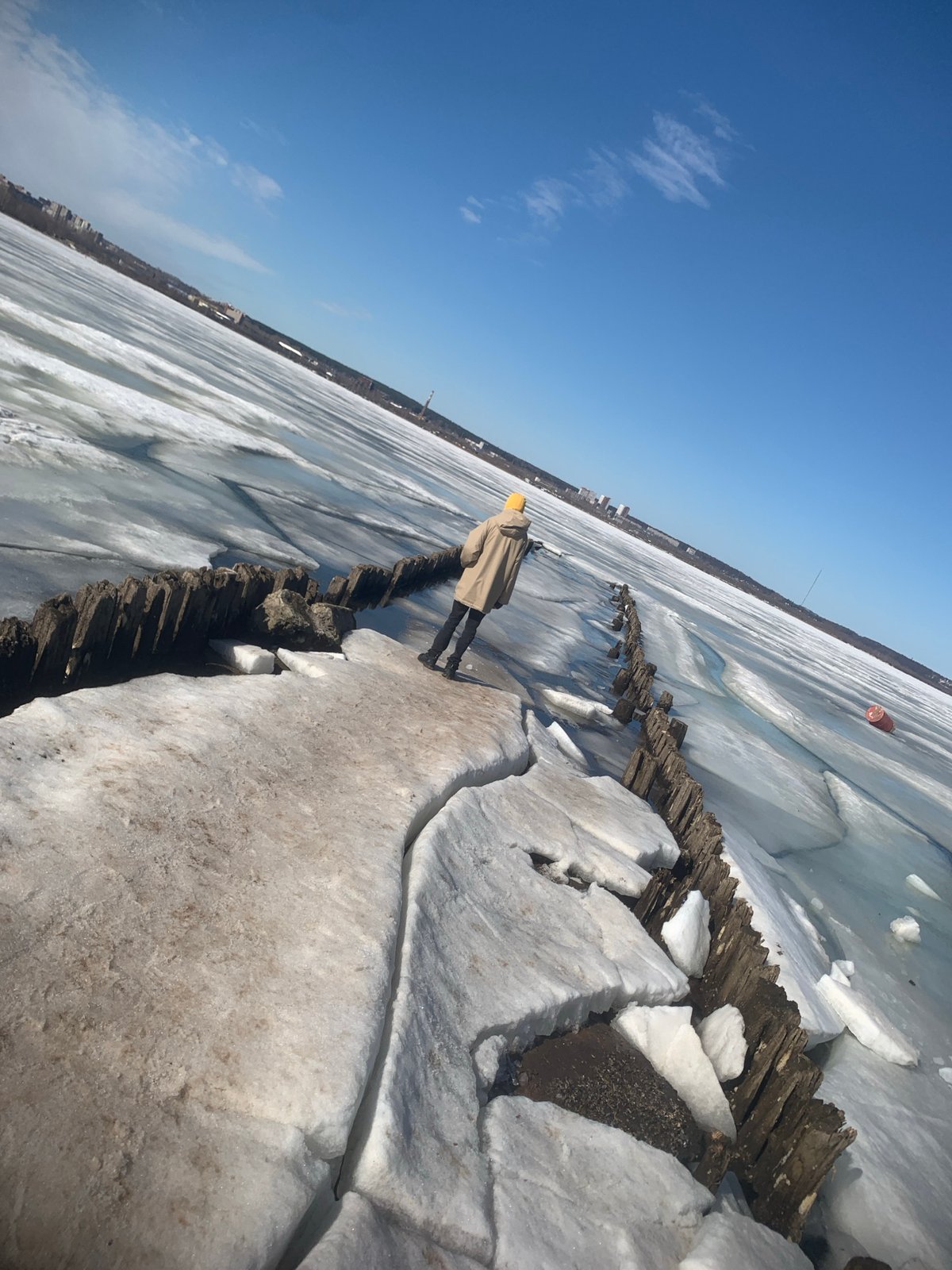 Person walks frozen breakwater at Izhevsk Pond during early morning