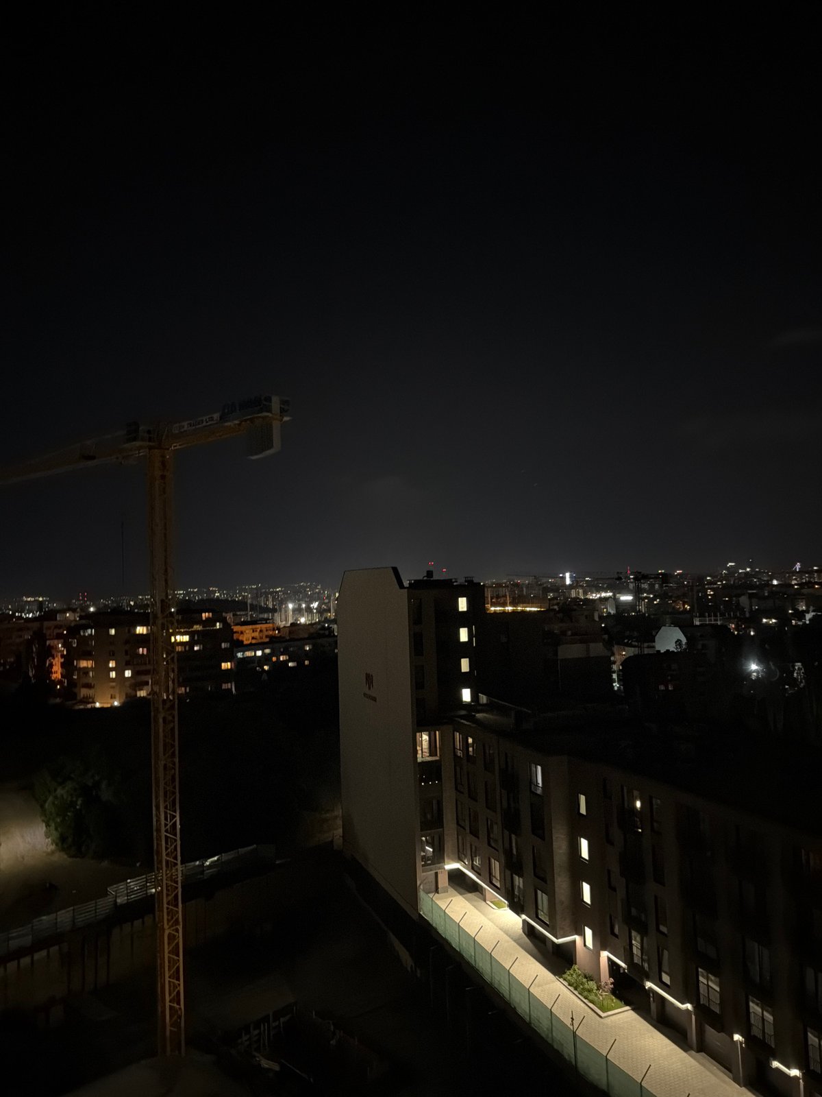 Sofia streets at night: cranes, lamplight, and a parked BMW