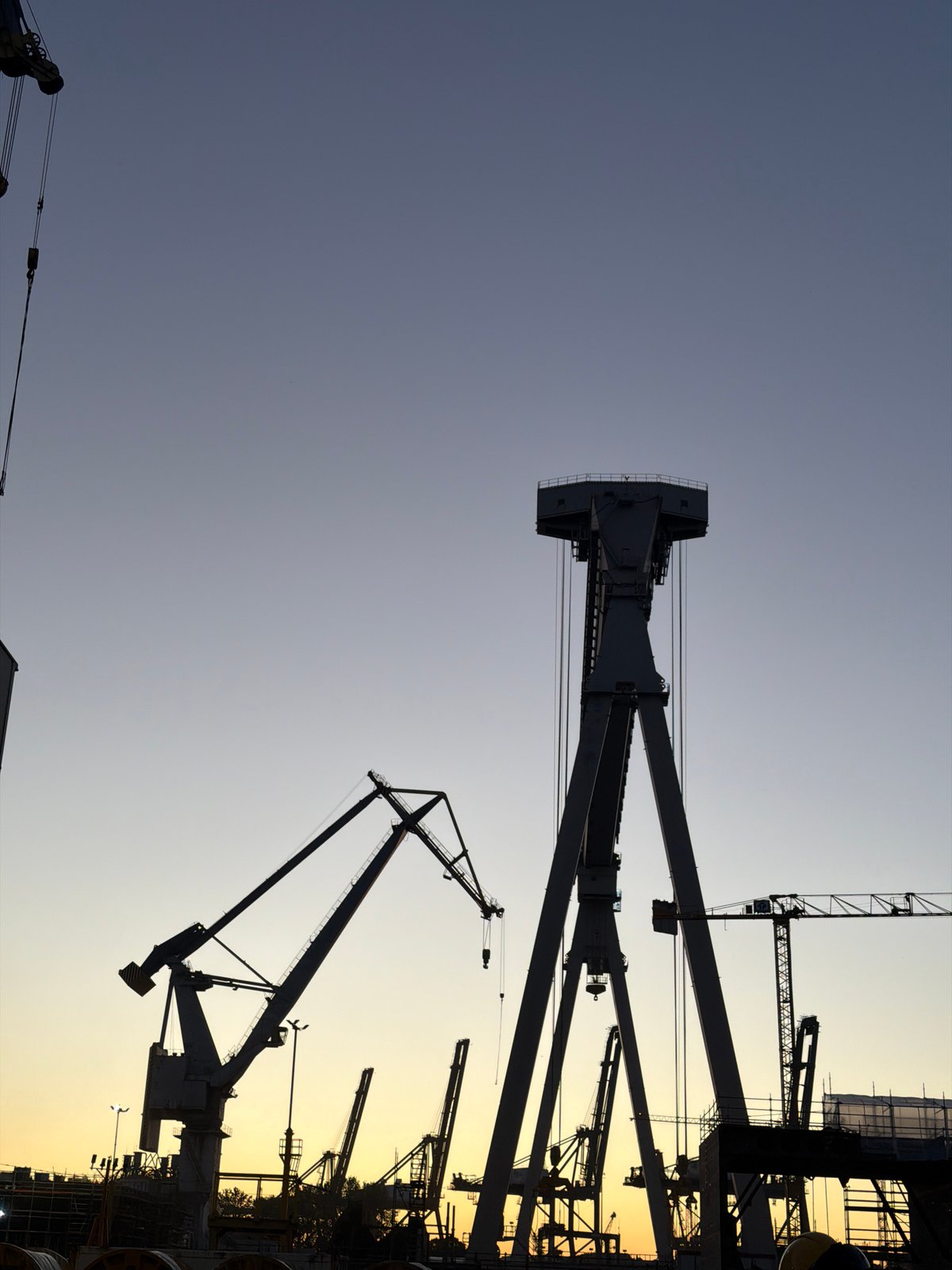 Gdynia shipyard cranes cut silhouettes against a twilight sky