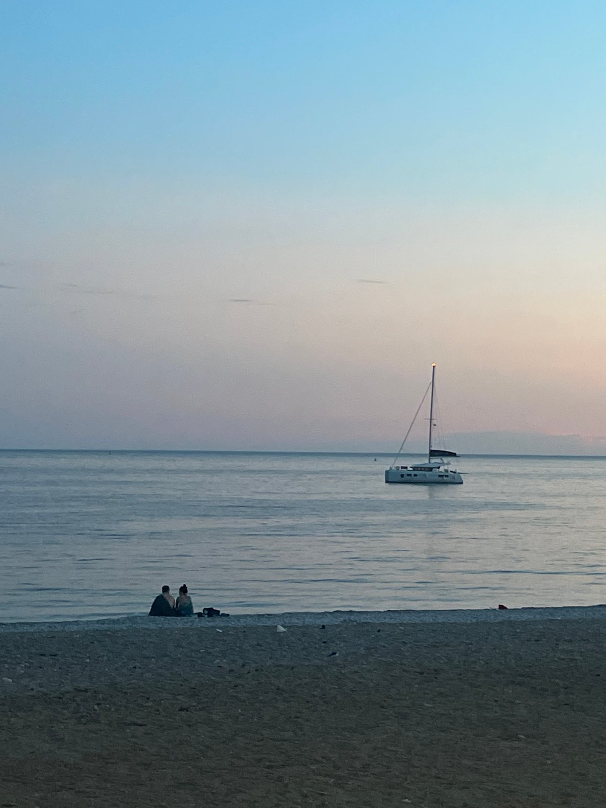 Twilight captured along Budva's Adriatic coastline with sailboats and city lights