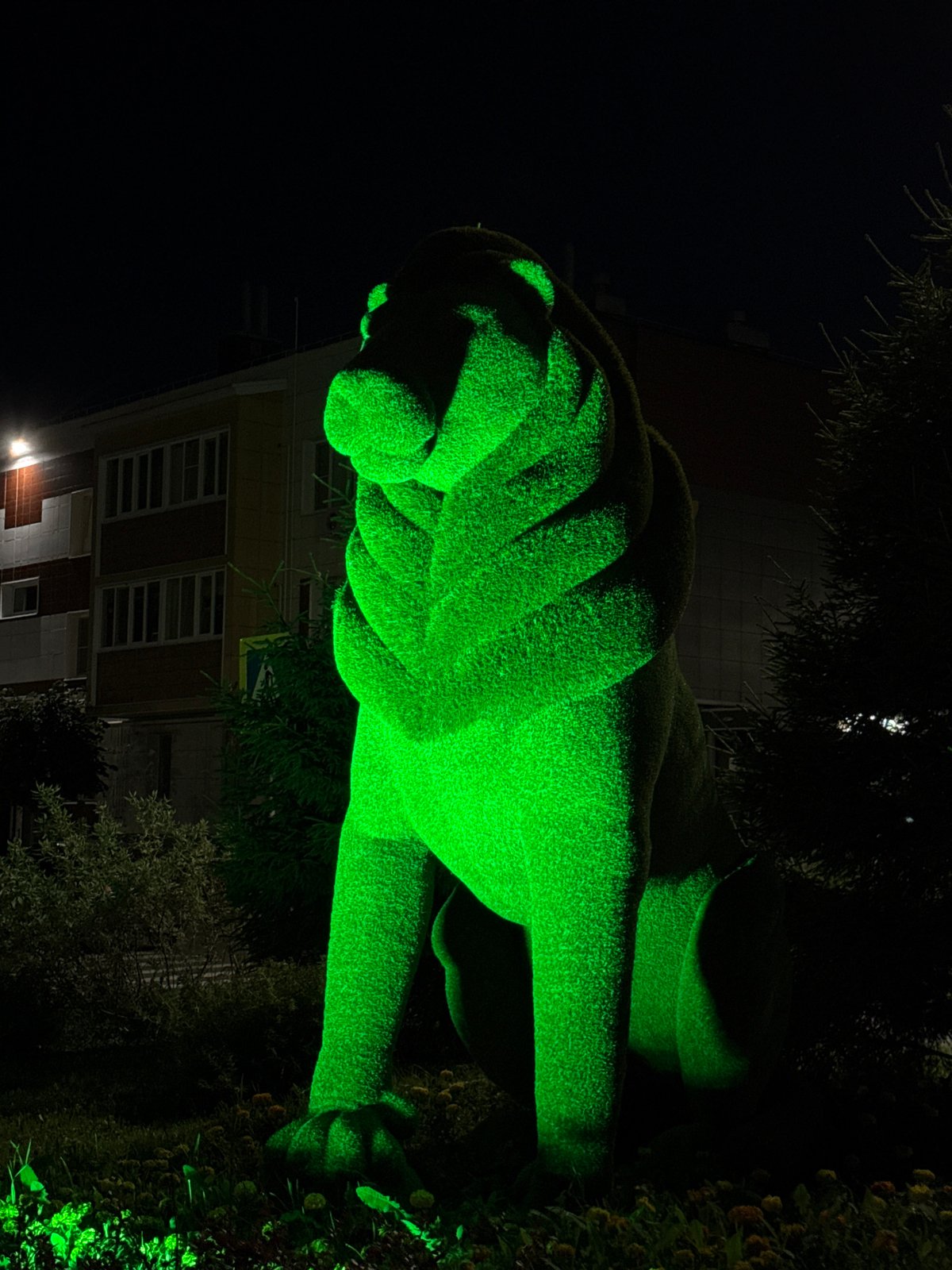 Green-lit topiary animals glow in a Russian park at night